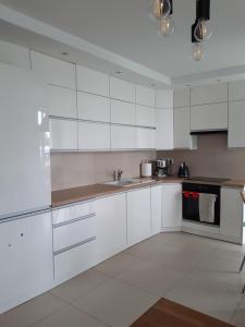 a white kitchen with white cabinets and a sink at Sanshiro apartment in Gdańsk