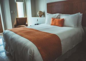 a bedroom with a large bed with an orange pillow at Hotel Parador de Alcalá in Oaxaca City