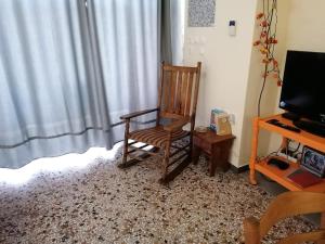 a wooden rocking chair sitting in front of a window at Savvas in Nafplio