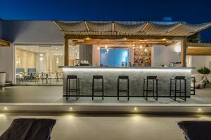 a bar with stools in a room with a bar at Lianos Village in Agios Prokopios