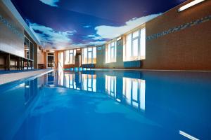 a swimming pool with blue lighting in a building at Hotel Slunce - wellness s bazénem, pivovar Morous a bowling in Rýmařov