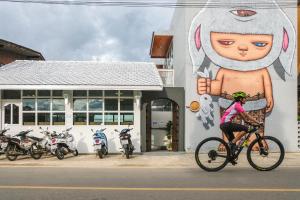 a woman riding a bike in front of a building with a mural at PaiApartHotel in Pai
