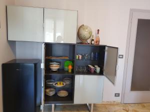 a kitchen with white cabinets and a shelf with dishes at Giolitti Luxury Apartment in Cuneo +19 photos