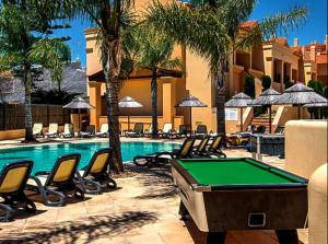 a pool table and lounge chairs next to a swimming pool at Praia da Luz Mar e Sol Apartamento in Luz
