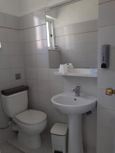 Baño blanco con aseo y lavamanos en Diana Rooms, en La Canea