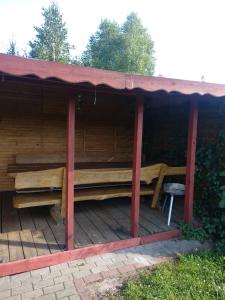 a wooden pavilion with a bench on a deck at Domki Orla in Pasym