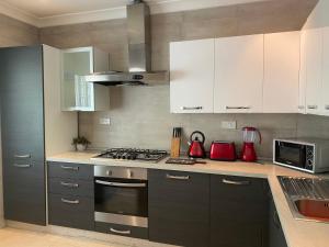 a kitchen with white cabinets and a stove top oven at -A- Bakerstreet- Beautiful Two Bedroom Apartment in Accra