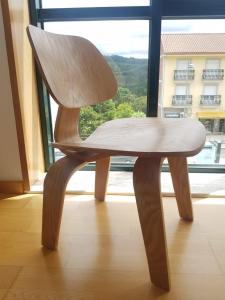 una silla de madera sentada frente a una ventana en PENSION ROSELLA, en O Pedrouzo