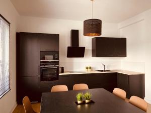 a kitchen with black cabinets and a table with chairs at Avenue Rops in Namur