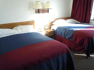 two beds in a hotel room with red curtains at Travelodge by Wyndham Grand Rapids North in Grand Rapids
