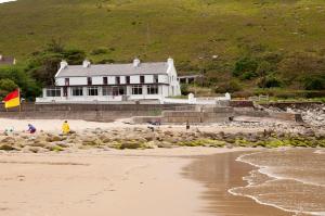 a white house on the beach with people on the sand at The Strand, Dugort Achill in Achill