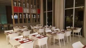 a dining room with white tables and white chairs at Apê na Barra, ao lado do Parque Olímpico, Jeunesse Arena, ar, wi fi, tv a cabo, microondas in Rio de Janeiro