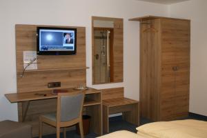 Zimmer mit einem Schreibtisch und einem TV an der Wand in der Unterkunft Landhotel Gasthof Wittstaig in Gundelfingen