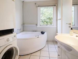 y baño blanco con bañera y lavadora. en 6 person holiday home in G rlev en Gørlev