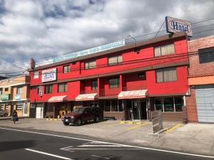 ein rotes Gebäude an der Ecke einer Straße in der Unterkunft Hostal Mitad del Mundo in Cayambe