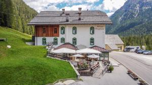 a large building on a hill next to a road at Rifugio Ospitale in Cortina dʼAmpezzo