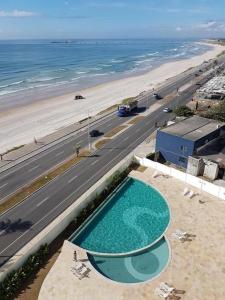 a swimming pool next to a beach and a road at Apartamento 02 quartos completo, BEIRA-MAR com piscina in Maceió