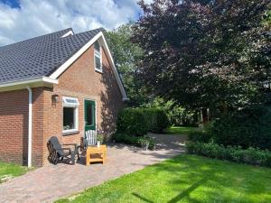 uma casa de tijolos com uma cadeira e uma mesa no quintal em Appartement Duinweg em Onstwedde