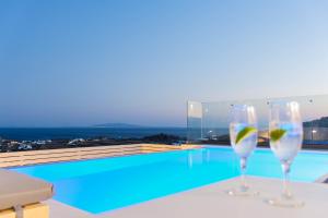 two wine glasses sitting on a table next to a swimming pool at Lofos Apartments in Platis Gialos