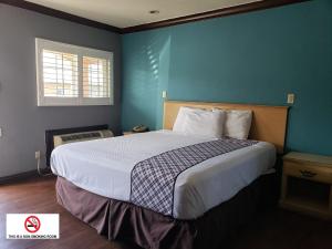 a bedroom with a large bed with a blue wall at Eagle Inn Motel in Long Beach