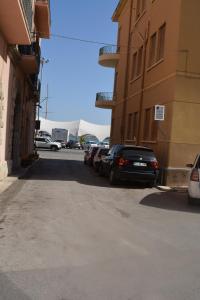 un parcheggio con auto parcheggiate accanto a un edificio di AL CIVICO 1 APARTMENTS a Trapani