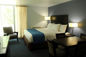 een hotelkamer met een bed, een bureau en een tafel bij Travelodge by Wyndham Water's Edge Hotel - Racine in Racine