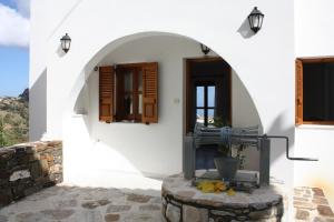 einen Eingang zu einem weißen Gebäude mit Torbogen in der Unterkunft Matina - Stavros Traditional Houses in Kóronos