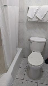 a white bathroom with a toilet and a bath tub at Eagle Inn Motel in Long Beach