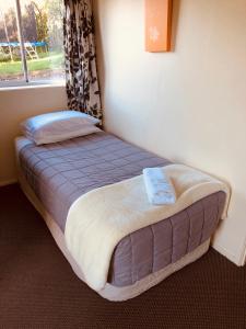 Waiheke Island Motel في Ostend: سرير صغير في غرفة مع نافذة