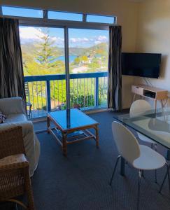 uma sala de estar com um sofá, uma mesa e uma grande janela em Waiheke Island Motel em Ostend