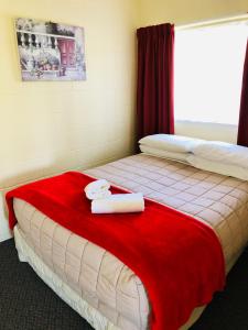 um quarto com 2 camas e toalhas num cobertor vermelho em Waiheke Island Motel em Ostend