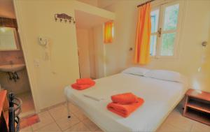 a bedroom with a bed with orange towels on it at Santorini Camping & Hostel in Fira