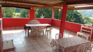 a patio with tables and chairs on a red wall at Chalézinhos São Roque in São Roque