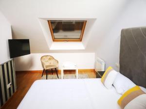 a bedroom with a bed and a chair and a tv at Golden Vedra Residences in Pontevedra