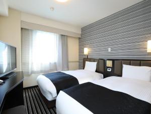 Cette chambre comprend 2 lits et une télévision à écran plat. dans l'établissement APA Hotel Saitama Shintoshin Eki-kita, à Saitama