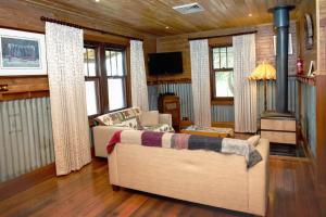 Una sala de estar con un sofá y una estufa. en Colby Cottages, Wooragee near Beechworth, en Wooragee