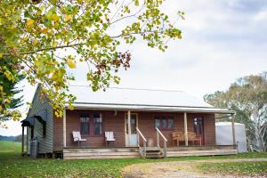Casa de madera con porche y 2 sillas en Colby Cottages, Wooragee near Beechworth, en Wooragee