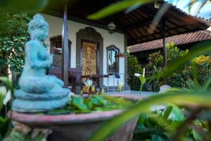 a statue in front of a house with a fountain at Ina Inn in Ubud