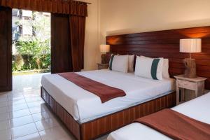 a bedroom with a large bed with a wooden headboard at Ina Inn in Ubud