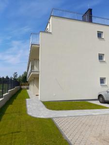 ein weißes Gebäude mit grünem Rasen daneben in der Unterkunft Milo Mare Apartaments in Mielno