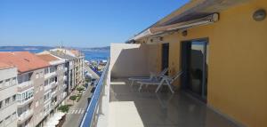 a balcony with a chair on the side of a building at Apartamento Exclusivo Bueu Centro, 50M playa in Bueu