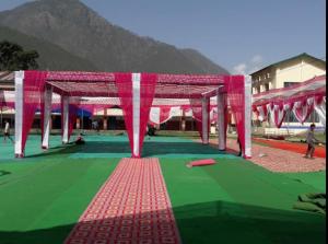 un pabellón con un campo verde y rojo con una montaña en Hotel Utsav Palace en Uttarkāshi