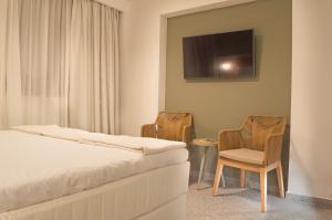 a bedroom with a bed and two chairs and a tv at Eco Green Residences & Suites in Toroni