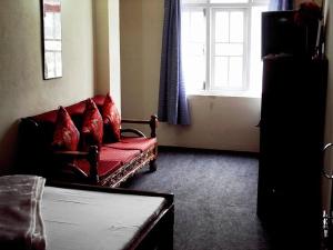 ein Wohnzimmer mit einem roten Sofa und einem Fenster in der Unterkunft Very Homely Hotel for Tourists in Gangtok