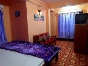 - une chambre avec un lit, une chaise et une télévision dans l'établissement Very Homely Hotel for Tourists, à Gangtok