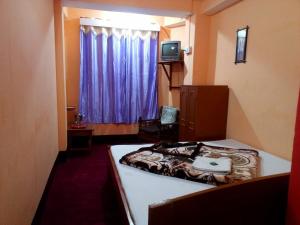 Kleines Zimmer mit einem Bett und einem Fenster in der Unterkunft Very Homely Hotel for Tourists in Gangtok