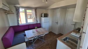 a living room with a purple couch and a table at Mobilhome Victoria Camping Lanterna in Poreč