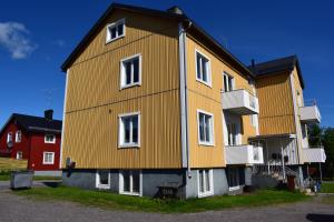 Una gran casa amarilla con ventanas blancas en una calle en Apartment with shared bathroom in central Kiruna 1 en Kiruna