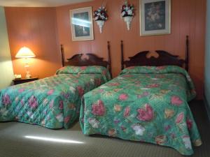 a bedroom with two beds with green comforter at Northland Motel Bay City-Kawkawlin in Kawkawlin