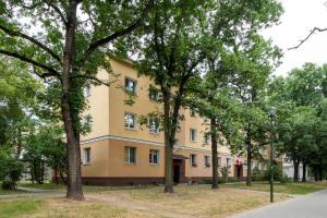 un edificio giallo con alberi di fronte di 404 Rooms Obrzezna Mokotow a Varsavia